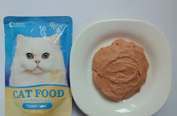 Tuna cat food pouch shown beside a plate of tuna pate