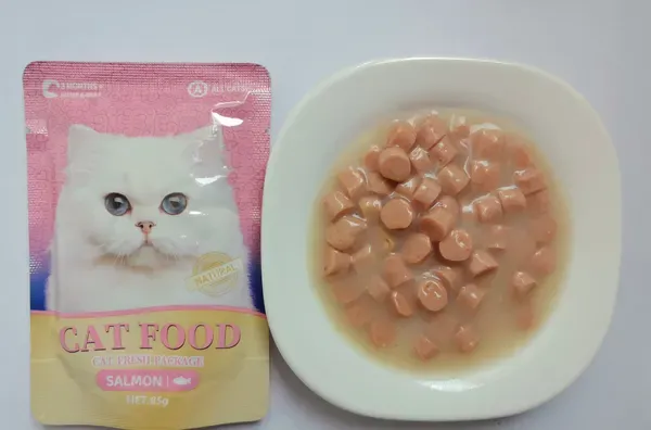 Cat food pouch with chicken chunks in gravy plated alongside
