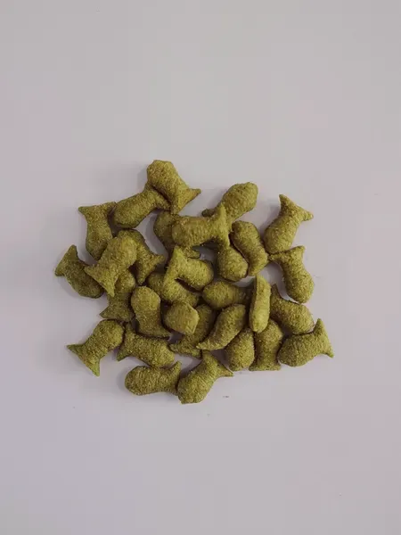 Green vegetable-flavoured dental pellets in a loose pile
