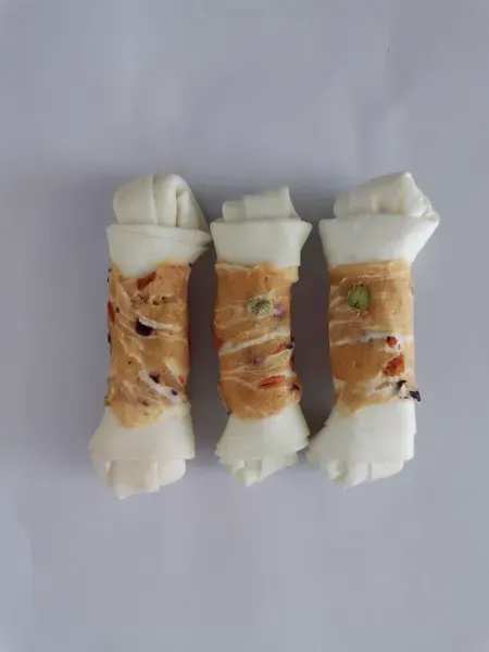 Knotted rawhide bones wrapped in light-coloured meat